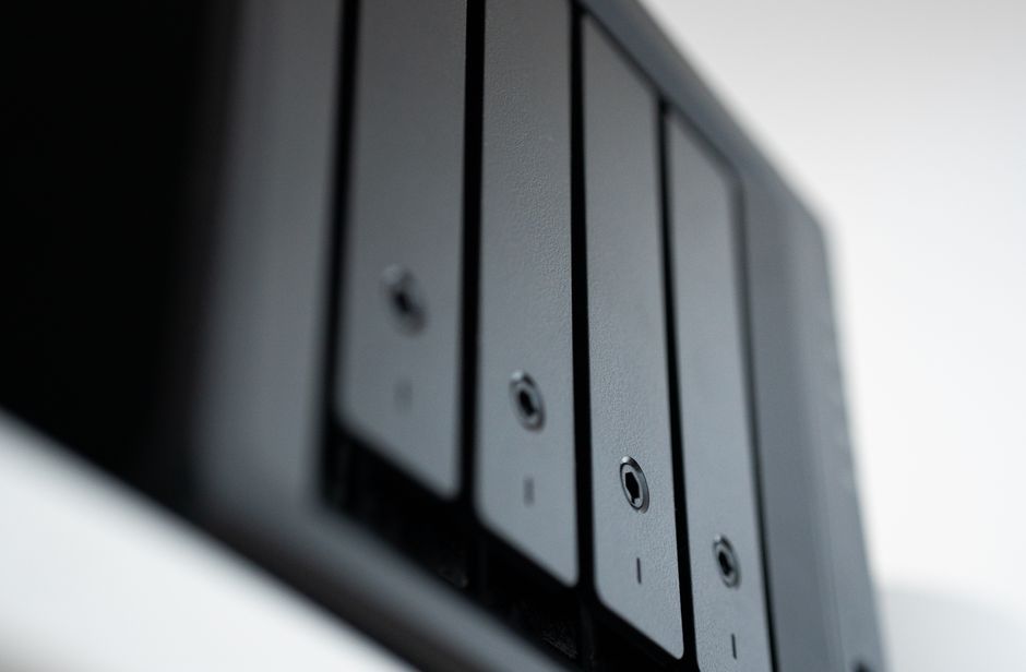Synology NAS cihazının ön panelindeki yan yana dizilmiş gri renkli butonlar.